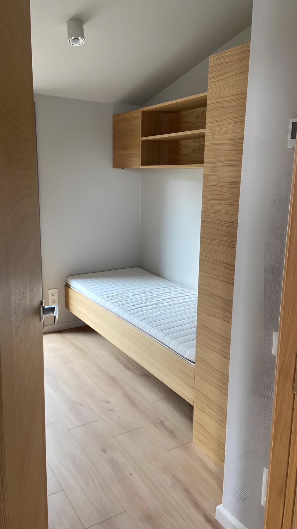 Kompakter Schlafbereich mit integriertem Stauraum und heller Holzoberfläche.