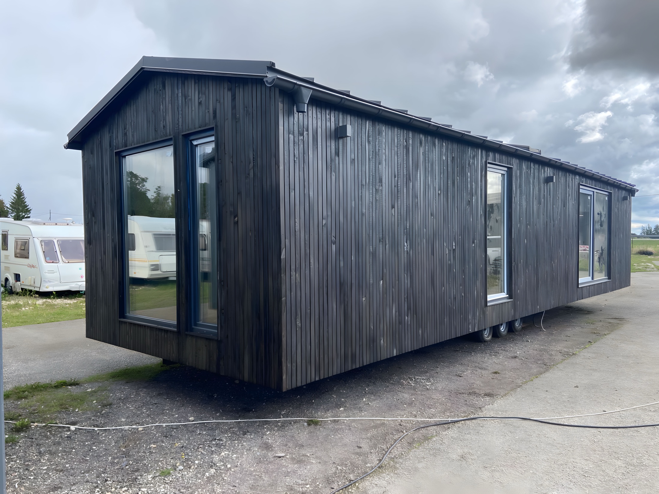 Dunkles Polarnest Haus mit klarer Holzfassade und großem Fenster.